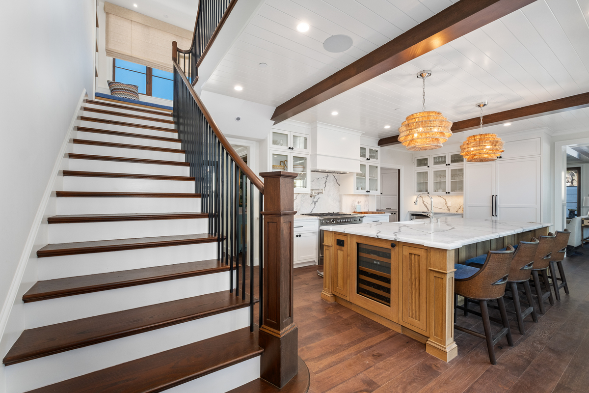 Custom white-oak island and open stair with beamed ceiling